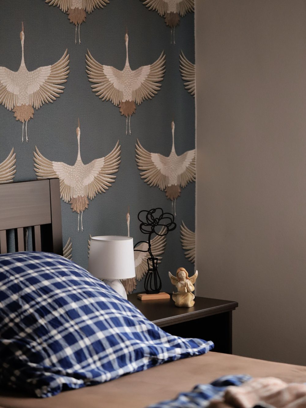 Contemporary bedroom with grey wallpaper featuring white cranes above a wooden headboard