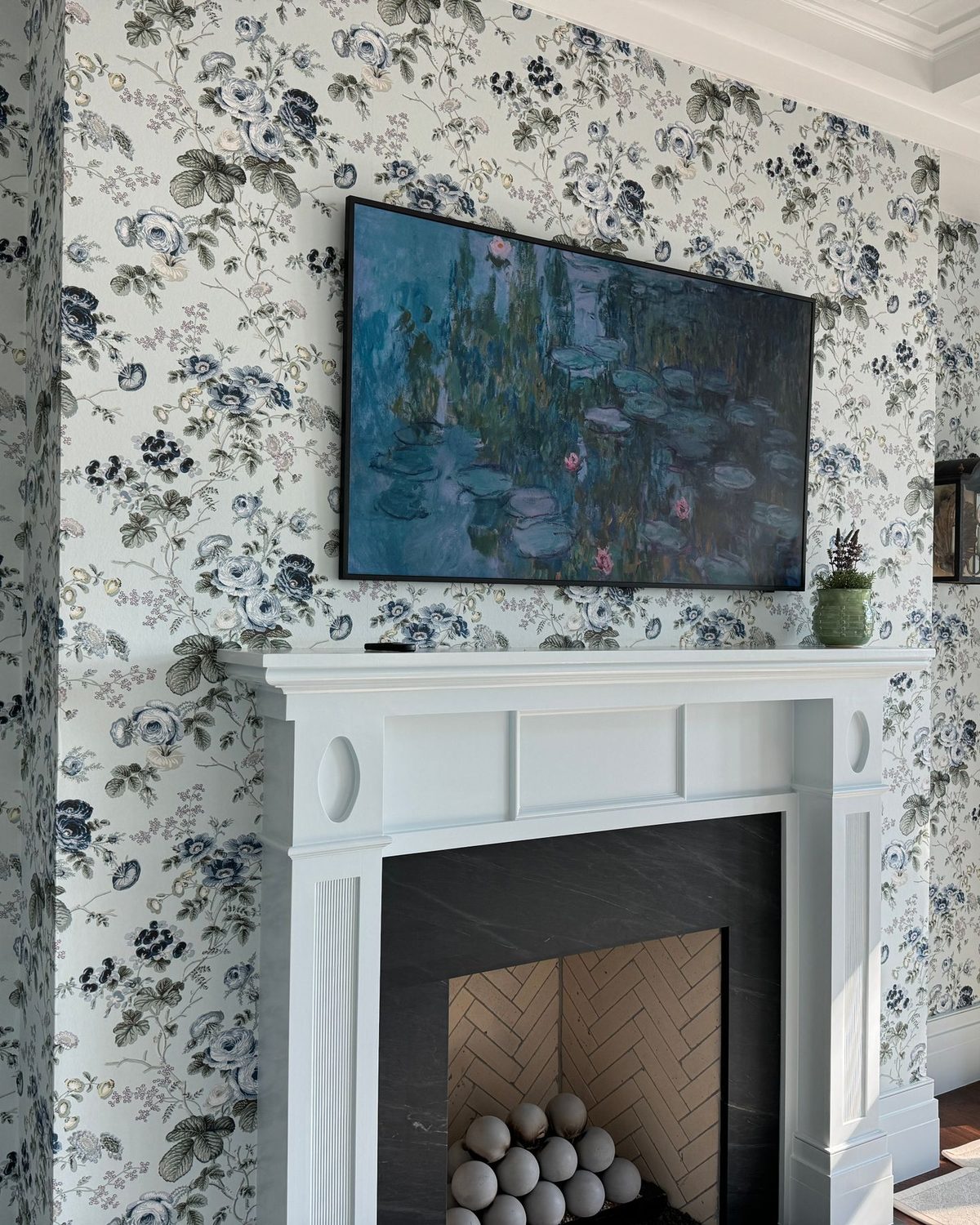 Living room with navy-and-white floral chinoiserie wallpaper around a classic white fireplace mantel