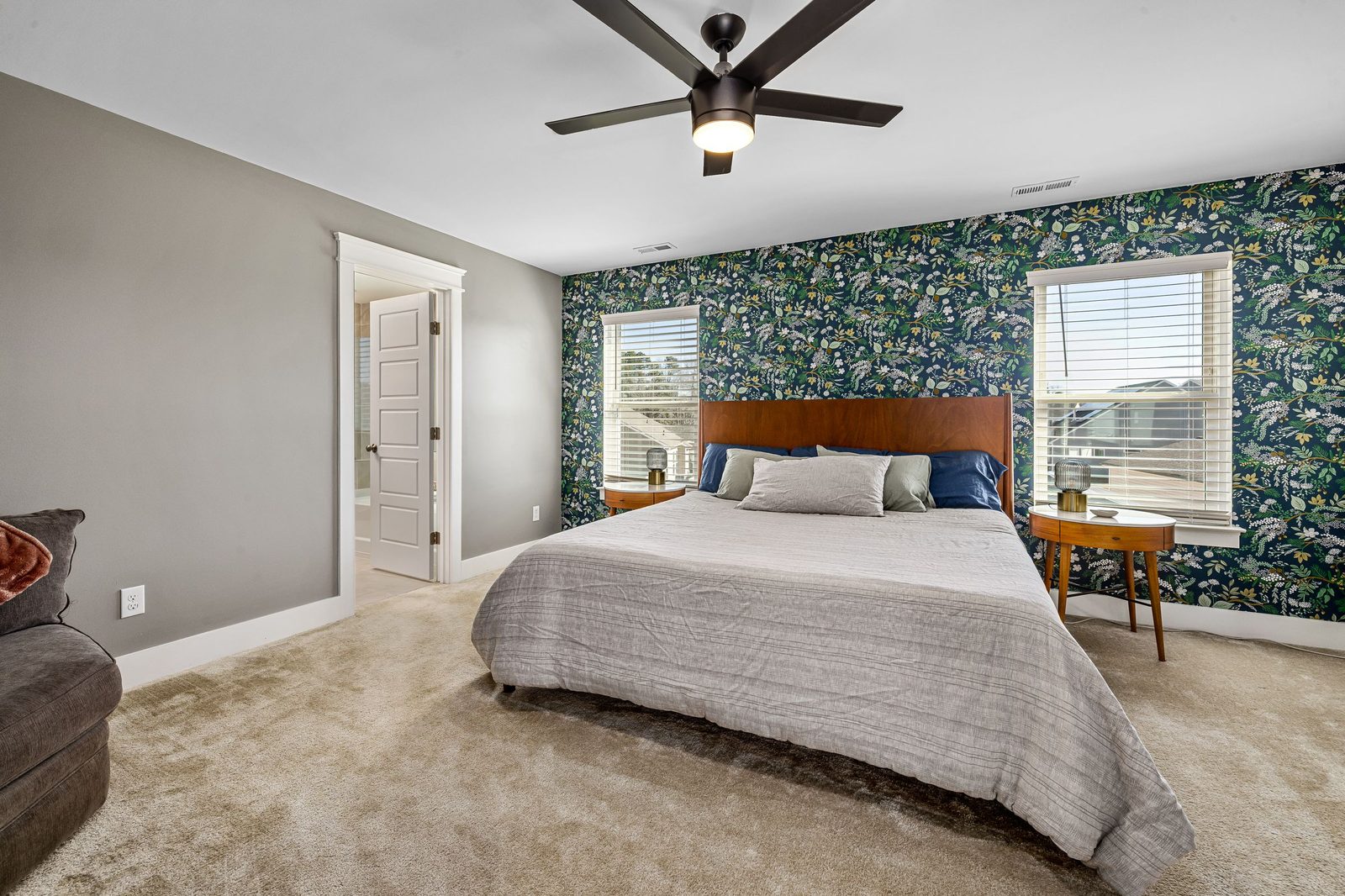 Bright bedroom with a botanical feature wall behind the bed, soft grey walls and plush carpet