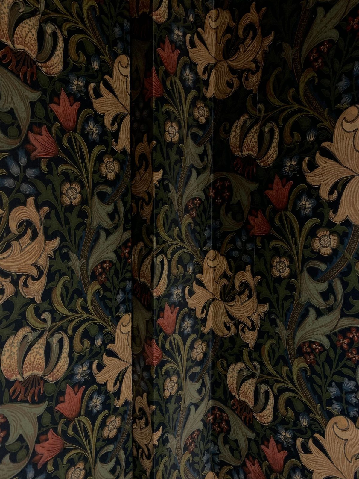 Close view of a richly colored botanical wallpaper with deep plum, teal and terracotta tones